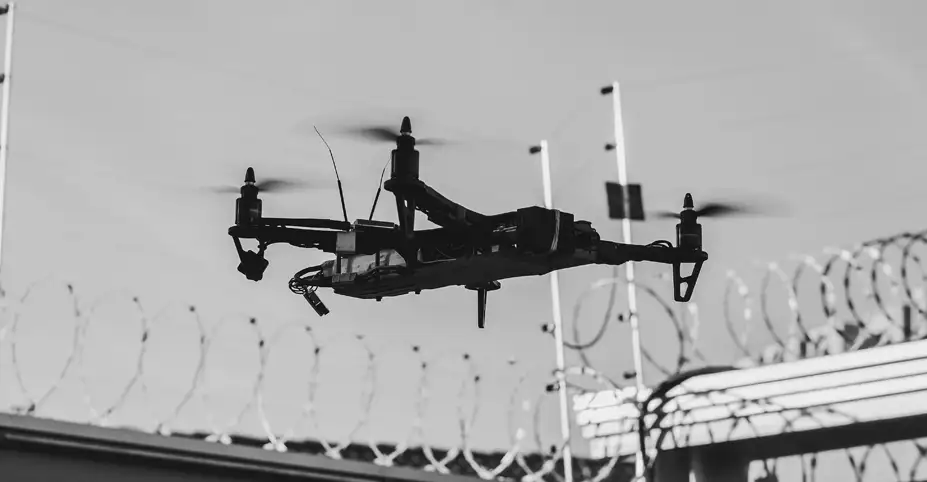 Black High-Tec drone flying above wired gates